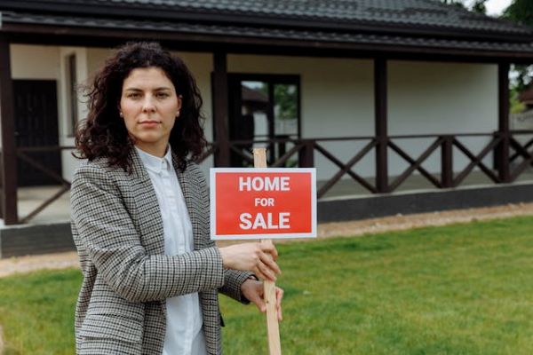 Female agent holding a home for sale sign 600 Pexels