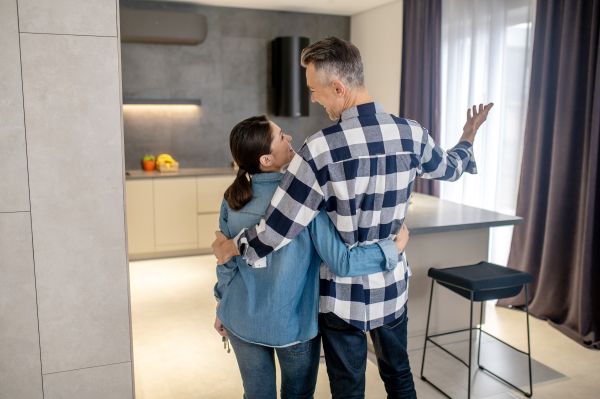 Happy moment back view man gesturing hugging woman with keys looking each other 600 Freepik