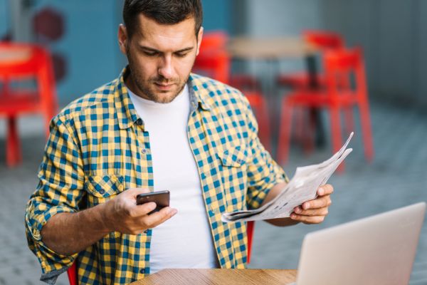Man with phone and newspaper 600 Freepik