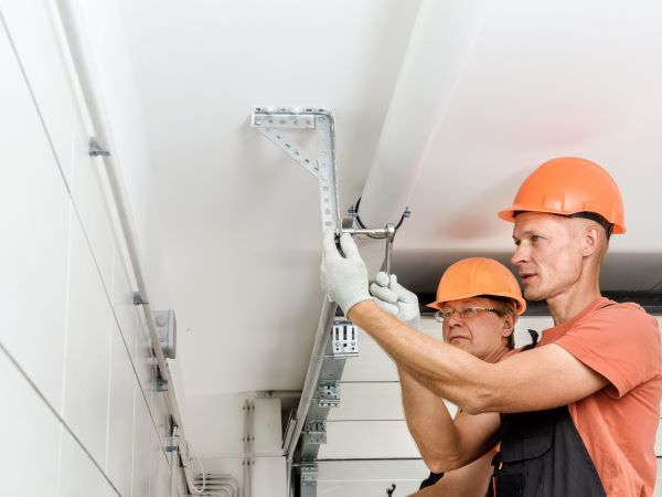 Technicians fixing garage door tracks Canva