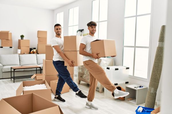 Two happy men carrying moving boxes 600 Freepik