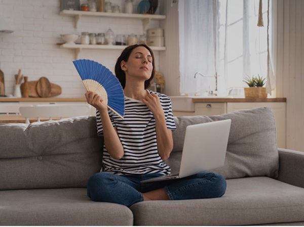 Woman fanning herself in a warm room Canva