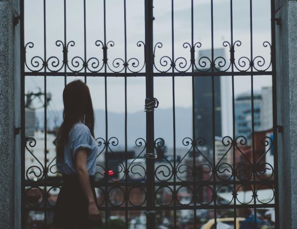 Woman standing beside gate 600 Pexels